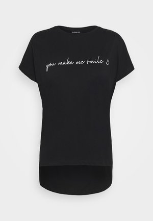 Sort T-shirt med korte ærmer med hvidt kursivskrift "you make me smile" og et lille smilende ansigt foran.