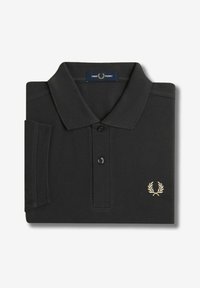 Polo negro hecho de tejido texturizado, con un cuello de dos botones, logotipo bordado en oro en el lado izquierdo del pecho y mangas dobladas.