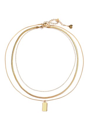 Gouden meerlagige ketting met drie verschillende kettingen: één glad, één met textuur en één met een rechthoekige charme.