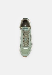 Green suede sneaker with a rounded toe, mesh accents, laced front, and rubber sole. Features branding on the tongue and side.
