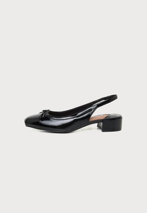 Zapato slingback negro de charol con tacón bajo de bloque y pequeño lazo decorativo en la puntera redondeada.