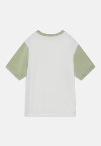 Bílý tričko s krátkým rukávem, světle zelenými rukávy a výstřihem, s hladkým povrchem a jednoduchým designem bez viditelných vzorů nebo akcentů.