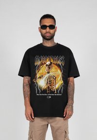 Sort grafisk t-shirt med et skeletdesign i orange og gule elementer, lynakcenter og fed tekst. Korte ærmer og afslappet pasform.