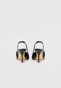Mustat nahkaiset slingback-korkokengät, joissa on terävä kärki ja hoikka stiletto-korko. Sujuva pinta ja minimalistikot, jossa on vaaleanruskea sisäpohja.
