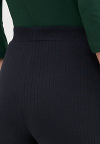 Des leggings côtelés noirs dotés d'une taille haute et d'un tissu texturé, conçus pour le confort et l'elasticité. Conviennent à diverses activités.