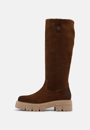 Stivale in suede marrone alto fino al ginocchio con suola chunky beige, presentante una punta tonda e un dettaglio a bottone in cima per la chiusura.