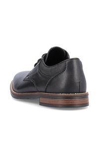 Chaussure en cuir noir avec un bout arrondi, un panneau texturé et une semelle avec accent marron. Conçue avec des lacets et une cheville rembourrée.