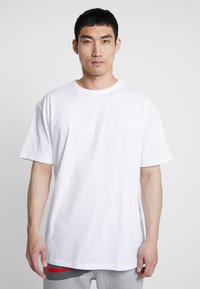 T-shirt in cotone bianco con una vestibilità comoda, maniche corte e scollatura rotonda. Texture liscia, senza motivi o dettagli visibili.