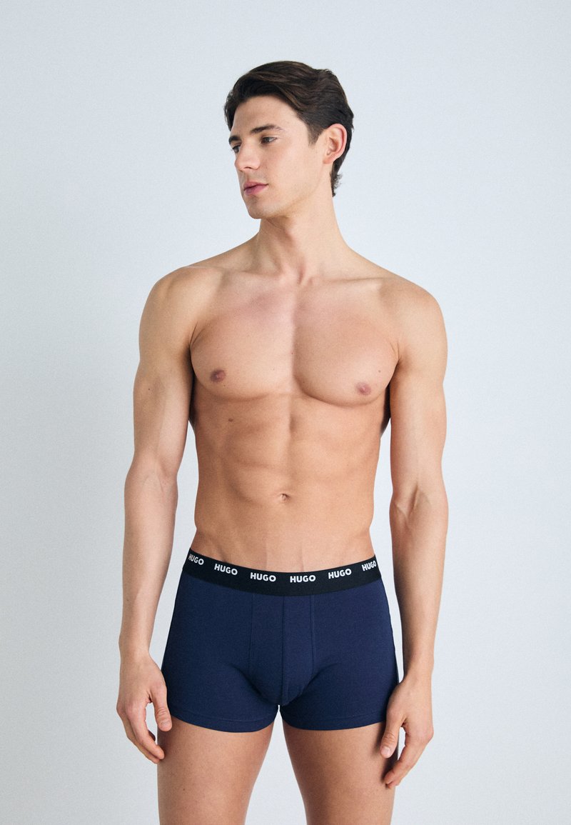 Marineblaue Boxershorts aus weicher Baumwolle, mit einem schwarzen Bund und "HUGO"-Logo. Glatte Textur, körperbetontes Design, mittelhohe Form.