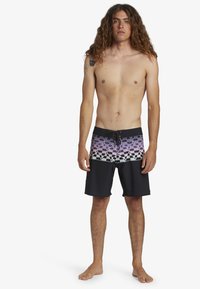 Svarta badshorts med ett geometriskt gradientmönster i lila och vitt. Tillverkade av texturerat tyg med midjeresår och snörning.