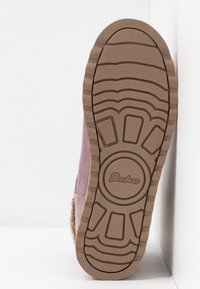 Sole boty v hnědé gumě s texturovaným vzorem proti skluzu. Svršek z jemně růžového materiálu, s kožíškovými akcenty podél stran a kolem kotníku.