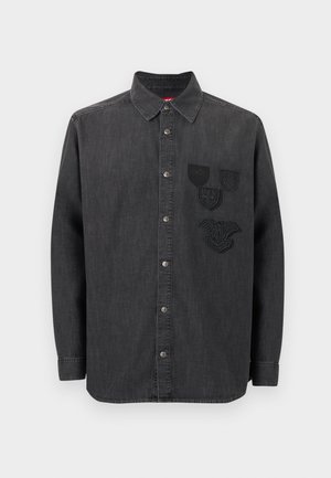 Black denim shirt featuring a button-up front, long sleeves, a collar, and three embroidered patches on the left chest. Textured fabric.