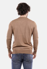 Maglione marrone chiaro con maniche lunghe e scollatura rotonda. Realizzato in un tessuto liscio, presenta una silhouette aderente e polsini a coste.