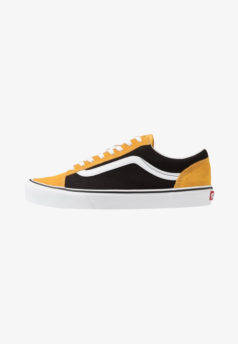 Low-top sneakers featuring a black canvas upper with yellow suede accents, white side stripe, and white laces on a white rubber sole.