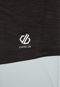 Haut de sport en tissu technique noir avec une texture lisse, arborant un logo « DARE2B » blanc et des coutures incurvées. Section inférieure bleu clair visible.