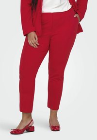 Röda skräddarsydda byxor i ett lätt material, med en figurnära design och avsmalnande ben, kombinerade med matchande glänsande röda slingbacks.