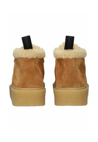 Stivaletti in suede marrone con una morbida fodera in pelliccia color crema, suole in gomma piatta e linguette nere sul retro con il nome del marchio.