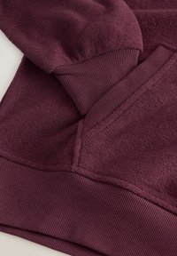 Bordeaux sweatshirt med en blød, struktureret overflade og ribbede manchetter og bund. Detaljeret syning langs sømmene for holdbarhed.