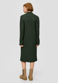 Długa, ciemnozielona sukienka dzianinowa z kołnierzykiem, opadającymi ramionami i długimi rękawami. W zestawie z beżowymi botkami za kostkę z teksturowanymi bokami.