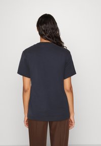 Camiseta de manga corta azul marino de algodón, con un clásico cuello redondo, corte relajado y sin logotipos ni patrones visibles.