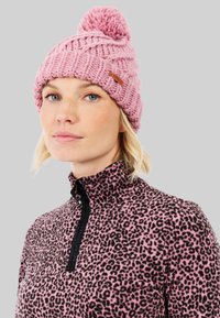 Nertas rožinis kepurė su pom-pomu viršuje ir struktūrizuota raštine. Nešiojama su juodu ir rožiniu leopardo rašto viršumi, turinčiu pusiau užtrauktuką.