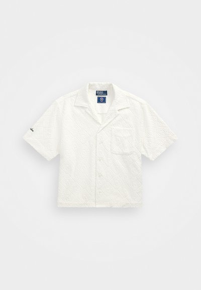 Balta trumpo rankovės marškinėliai, puošti tekstūruotu geometriniu raštu, su krūtine kišene ir sagų užsegimu, pagaminti iš lengvos medžiagos.