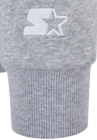 Tissu de sweatshirt gris avec une manche côtelée texturée, arborant un logo brodé blanc représentant une lettre 'S' stylisée et une étoile.