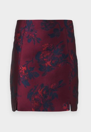 Jupe à motif floral bourgogne avec des accents bleu marine, fabriquée en tissu lisse. Présente des fentes latérales et un motif floral texturé sur l'ensemble.