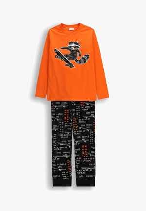 Pomarańczowa koszula z długim rękawem z grafiką szopa na desce do jazdy, połączona z czarnymi spodniami z wzorem desek do jazdy i białymi oraz pomarańczowymi napisami.