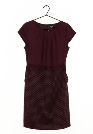Robe courte manches courtes violet foncé avec corsage plissé et jupe texturée à motifs suspendue sur un cintre noir sur fond blanc.
