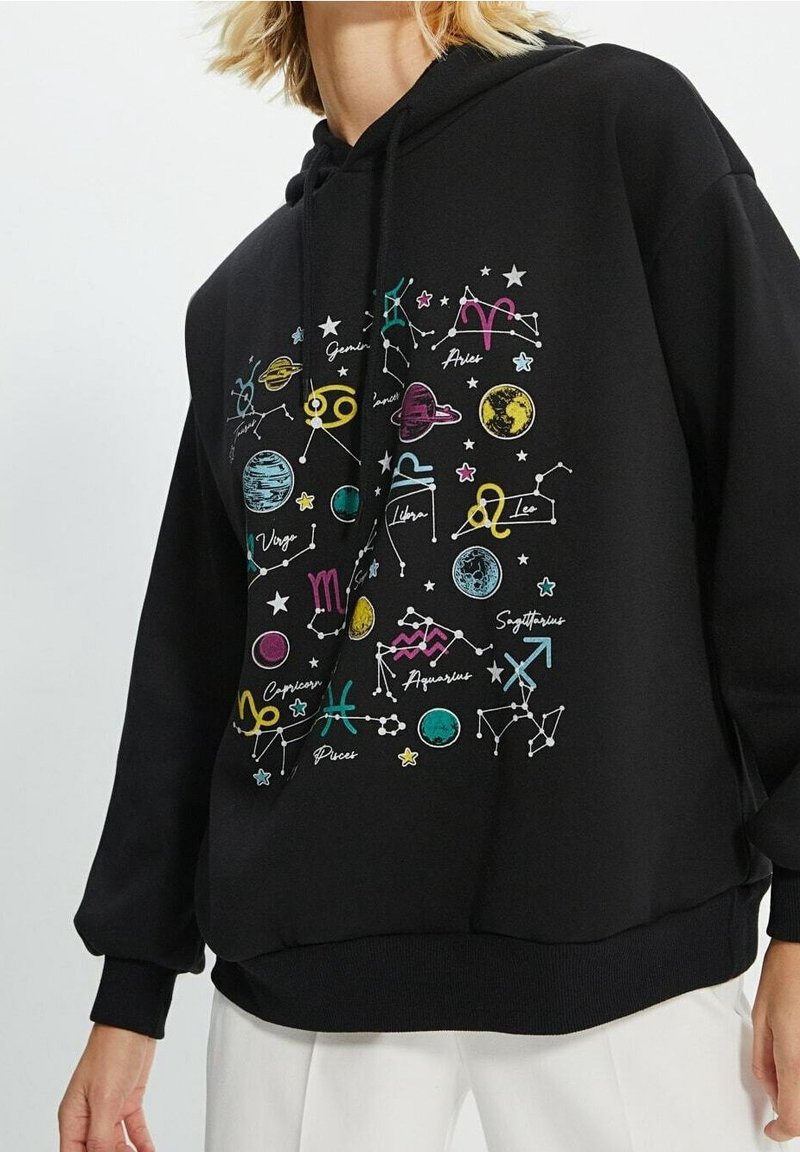 Sweat à capuche noir avec des signes du zodiaque colorés, des planètes et des étoiles imprimés sur le devant ; silhouette ample et poignets côtelés.