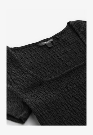 Melnas teksturētas augšdaļas ar kvadrātveida kakla izgriezumu, ar smalkām krokām un īsām piedurknēm. Audums izskatās mīksts un viegls.