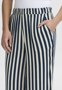 Navy and cream striped pants with an elastic waistband, wide legs, and side pockets. Fabric appears smooth with vertical patterning.