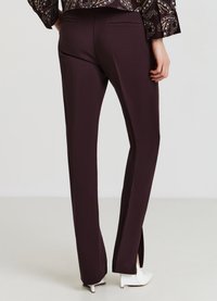 Pantalons ajustés bordeaux avec fentes latérales à l'ourlet, fabriqués en tissu lisse. Comprend deux poches arrière et une silhouette propre et ajustée.