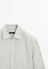 Hellegraues Leinenhemd mit weißen vertikalen Streifen, Button-Down-Kragen und einer einzelnen Knopfleiste vorne. Label im Kragen sichtbar.