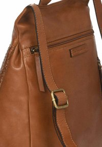 Bolso de cuero marrón con una textura suave, que cuenta con un bolsillo con cremallera y un detalle trenzado. Los herrajes dorados acentúan la correa para el hombro.