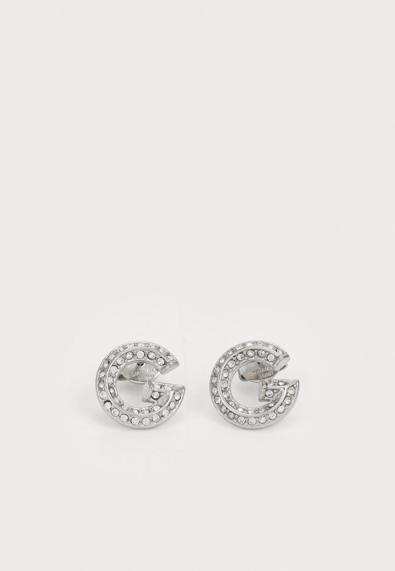 Orecchini a perno argento a forma di 'G', decorati con strass trasparenti lungo i bordi. Finitura in metallo liscia, con una texture lucida.