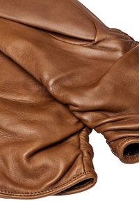 Braune Lederhandschuhe mit gerafften elastischen Handgelenken, die eine weiche Textur und nähtechnische Details auf einem weißen Hintergrund zeigen.