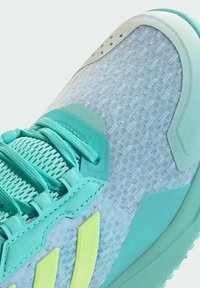 Jasnoniebieski but sportowy z teksturowaną siateczkową cholewką, turkusowymi akcentami oraz wyraźnym limonkowo-zielonym logo. Sznurowadła są plecione i płaskie.