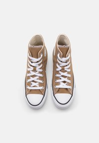 High-top sneakers in brown canvas with white laces, rubber toe cap, and black outsole. Features stitched seams and metal eyelets.