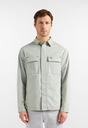 Lysegrøn, langærmet skjorte lavet af bomuld med to brystlommer og krave med knapper, med et lille emblem på venstre lomme.