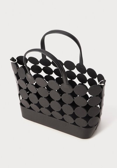 Sac fourre-tout noir avec un design circulaire perforé, en cuir, doté de double poignées et d'une section inférieure solide. Texturé et structuré.