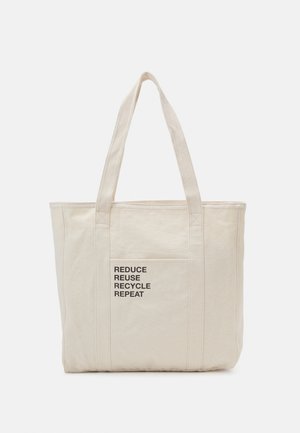 Canvas tote bag in light beige with two sturdy handles, featuring a front pocket and printed text: "REDUCE REUSE RECYCLE REPEAT."