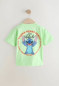 Grøn kortærmet T-shirt med en tegneseriefigur med udstrakte arme. Teksten lyder "‘Ohana betyder familie" med fede røde og sorte bogstaver.