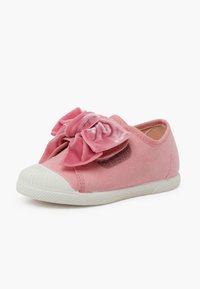 Scarpa in suede rosa con un grande fiocco in velluto rosa sulla parte anteriore, suola in gomma bianca e design a punta arrotondata.