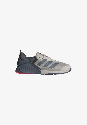 Baskets de sport gris clair et gris foncé avec trois bandes gris foncé sur le côté, empeigne en mesh et accent rouge sur la semelle.