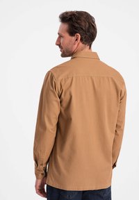 Lange mouwen bruine shirt van katoen, met een kraag, knoopmanchetten en een rechte zoom. Eenvoudig, klassiek ontwerp zonder patronen.