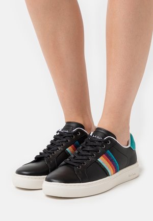 Sneakers in pelle nera con suola bianca, caratterizzati da una striscia multicolore sul lato e un accento verde acqua sul tallone. Design con lacci, texture liscia.