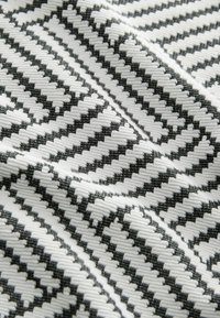 Tela tejida con un patrón de zigzag en blanco y negro; superficie texturizada con secciones alternas suaves y en relieve.