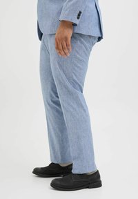 Helle blaue Leinenhose mit strukturierter Oberfläche, gerade geschnitten und mit dezenten Vordertaschen, kombiniert mit schwarzen Schuhen.